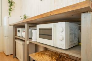 a shelf with two microwaves and a microwave on it at 照間Terumaの美しい海と太陽 Soleが目前に広がる和室ありの宿 TERUSOLEテルソーレ in Uruma