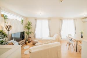 a living room with white furniture and a table at 照間Terumaの美しい海と太陽 Soleが目前に広がる和室ありの宿 TERUSOLEテルソーレ in Uruma