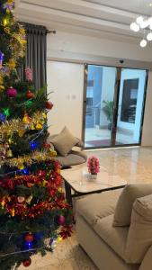 a christmas tree in a living room next to a couch at Rex&Rich Hotel and Suites in Umu Oma
