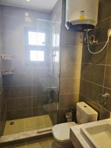 a bathroom with a shower and a toilet and a sink at Luxury Azha Ain Sokhna Villa - Pool & Garden Views in Ain Sokhna