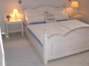 ein weißes Bett in einem Schlafzimmer mit zwei Nachttischen in der Unterkunft Morgensünn am Strand in Kühlungsborn
