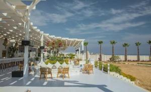 a white patio with chairs and tables and the beach at Luxury Azha Ain Sokhna Villa - Pool & Garden Views in Ain Sokhna +4 photos