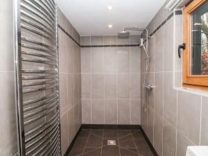 a shower in a bathroom with gray tiles at Owl Cottage in Woodbridge
