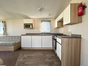 a kitchen with white cabinets and a couch at The Rochester - Uk51003 in Eastchurch