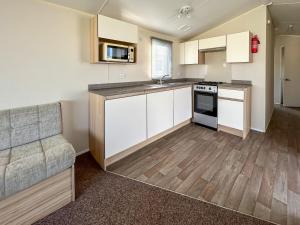 a kitchen with white cabinets and a couch in a room at The Rochester - Uk51003 in Eastchurch