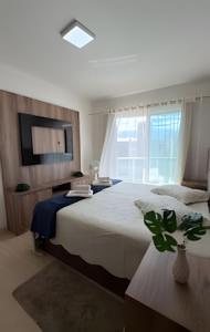 a bedroom with a large bed and a tv at Apto Copo Leite|3Q c|Sacada,Churrasqueira,na Aven in Piratuba