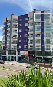two tall buildings in a city with a street at Apto Copo Leite|3Q c|Sacada,Churrasqueira,na Aven in Piratuba