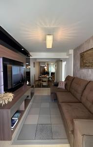 a living room with a couch and a television at Apto Copo Leite|3Q c|Sacada,Churrasqueira,na Aven in Piratuba