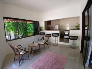 a living room with chairs and a table and a kitchen at Casa charme pipa in Pipa