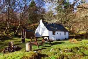 a small white house with a picnic table in front of it at Sawmill Cottage in Acharacle +2 photos