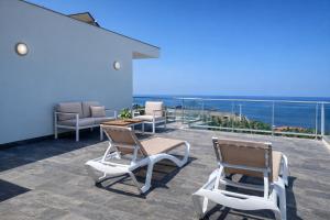two chairs and a table on a balcony with the ocean at Villa O Pomar with optional heated pool in Paul do Mar