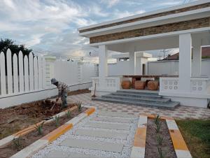 a man working in a yard in front of a house at Good Dream Guest Home in Phumĭ Toch