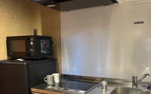 a kitchen with a microwave and a sink at COFFEE HOTEL Soundwave in Fujisawa