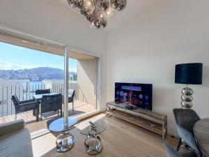 a living room with a couch and a television and a balcony at Design Apartment Archea Terrazza sul Lago Maggiore in Laveno-Mombello