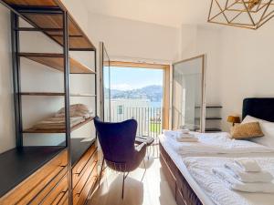 a bedroom with a bed and a chair and a window at Design Apartment Archea Terrazza sul Lago Maggiore in Laveno-Mombello