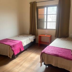 a room with two beds and a window at Morada 1000 - Pousada in Frutal