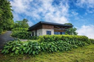 a brick house with a black roof on a hill at Private Mountain Cabin with Garden Views in Zarcero