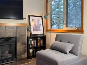 a living room with a chair and a fireplace at One Bedroom Mountain View Condo - Lodges at Canmore in Canmore