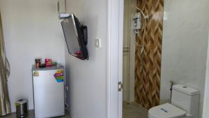 a small bathroom with a toilet and a tv on the wall at Ban Pai Khlung Resort in Chanthaburi +2 photos