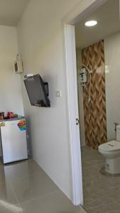 a bathroom with a toilet and a tv on the wall at Ban Pai Khlung Resort in Chanthaburi