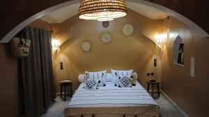 a bedroom with a large bed with a chandelier at La Colline Verte Dar Ait El Abass in Ouarzazate