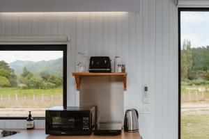 a kitchen with a counter with a microwave and a window at Omoho Stream X by Tiny Away in Kennedys Bay