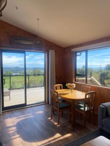 a dining room with a table and chairs and windows at Flax Ridge in Hokitika Airport