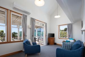 a living room with blue chairs and windows at City Apartment South Street in Nelson