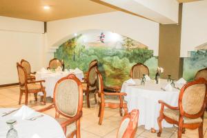a restaurant with white tables and chairs and a painting at Hotel Ruinas Resort in Huehuetenango