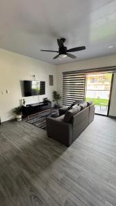 a living room with a couch and a ceiling fan at Riverside Apartments in Jacó