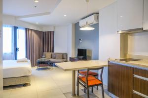 a kitchen and living room with a bed and a table at Top Floor Studio Non-Resort Unit Tambuli Tower D in Maribago