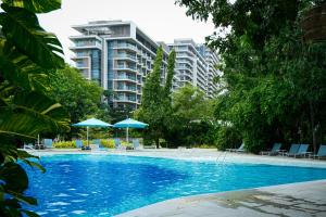 a swimming pool with chairs and umbrellas and a building at Top Floor Studio Non-Resort Unit Tambuli Tower D in Maribago