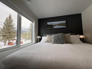 a bedroom with a large bed and a large window at New Luxury MountainView Downtown2B2B RooftopHottub in Canmore