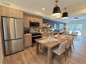 a kitchen with a table with chairs and a refrigerator at New Luxury MountainView Downtown2B2B RooftopHottub in Canmore