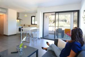 une femme assise sur un canapé dans un salon dans l'établissement Les Terrasses Du Grand Large, à Porto Pollo