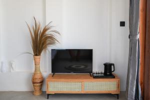 a tv sitting on top of a table with a vase at Ombara Resort Mentawai in Katiet