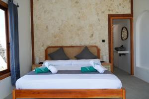 a bedroom with a large bed with green and white pillows at Ombara Resort Mentawai in Katiet