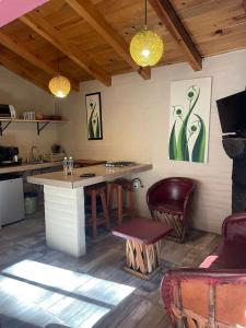 a kitchen with a table and a bar with chairs at Cabañas Quinta de Cuevas in Mazamitla +5 photos