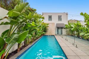 a swimming pool in front of a house with palm trees at Complete Host Middle Park House in Melbourne