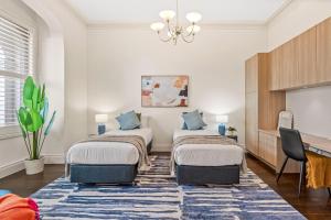 two beds in a room with a blue rug at Complete Host Middle Park House in Melbourne