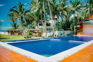 a swimming pool in front of a resort with palm trees at H&P Beach Resort in Pandan