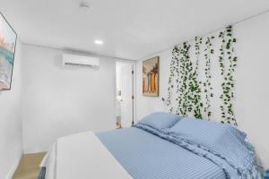 a white bedroom with a bed with a plant on the wall at The Oasis Signature in Miami