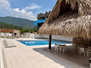 a resort with a straw umbrella and a swimming pool at Apartamento en Villeta in Villeta