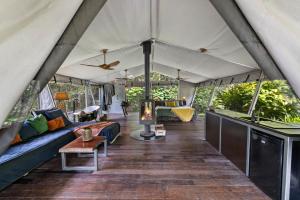 a living room of a tent with a couch and a fireplace at Starry Nights Luxury Camping in Woombye