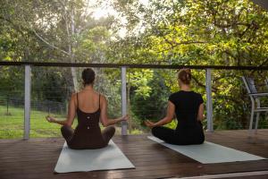 two women sitting on a deck doing yoga at Starry Nights Luxury Camping in Woombye