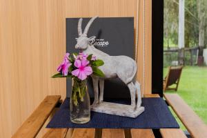 a vase with flowers and a statue of a goat at Tranquility Ranch by Tiny Away in Wolfdene +29 photos