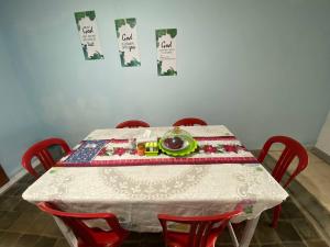 a table with red chairs and a plate of food on it at Wel home stay in Pulau Gilimota