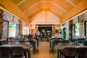 a dining room with tables and chairs and windows at H&P Beach Resort in Pandan