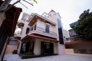 a white house with a balcony on a street at Đậu Homestay Phố Cổ in Ninh Binh +6 photos
