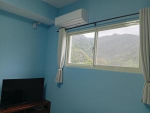a blue room with a window and a television at 宜蘭縣三星鄉遇雨魚民宿2932 in Gongzhao